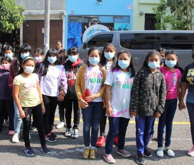 a group of children wearing face masks standing in a parking lot
