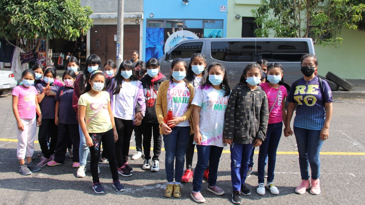 a group of children wearing face masks standing in a parking lot